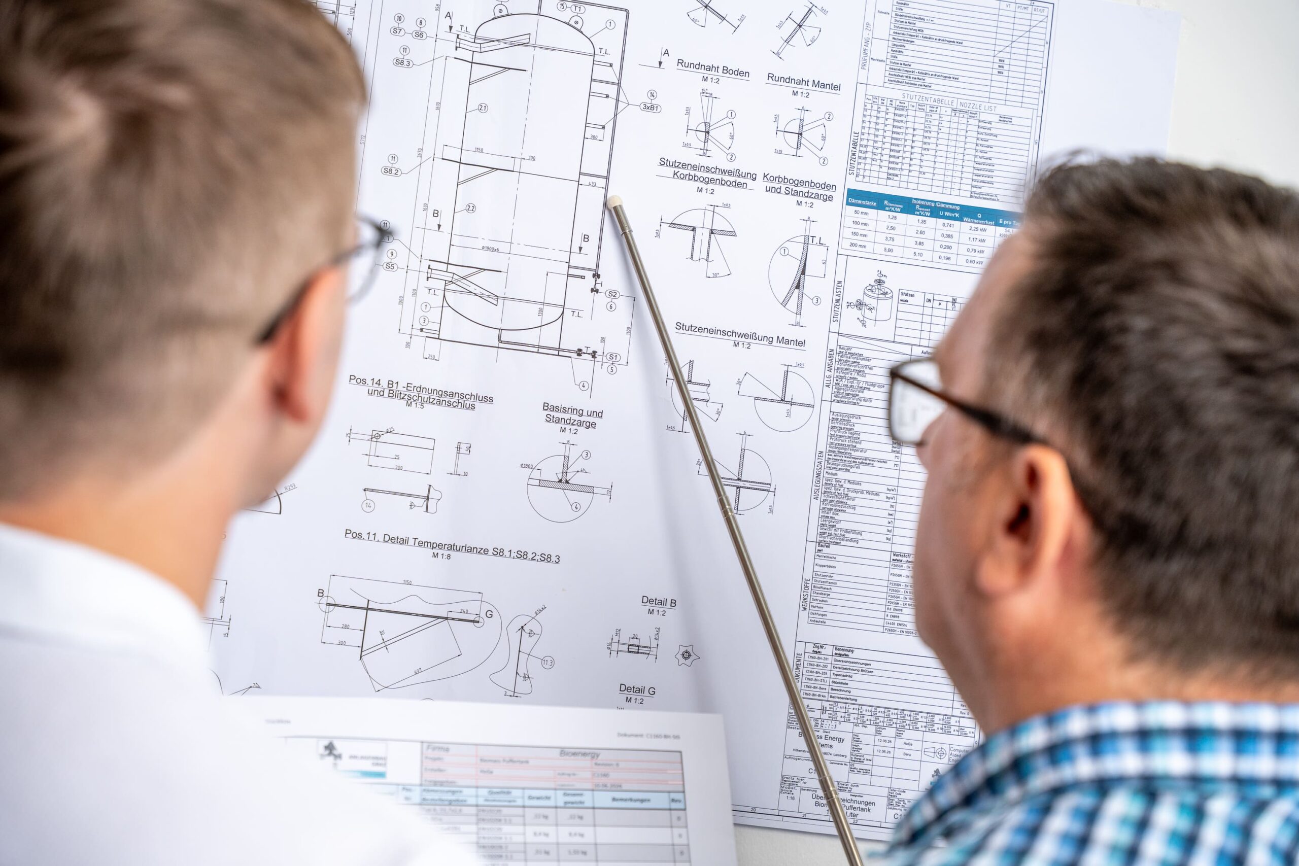 Zwei Mitarbeiter von PE Solutions besprechen die Detailzeichnung eines Behälters
